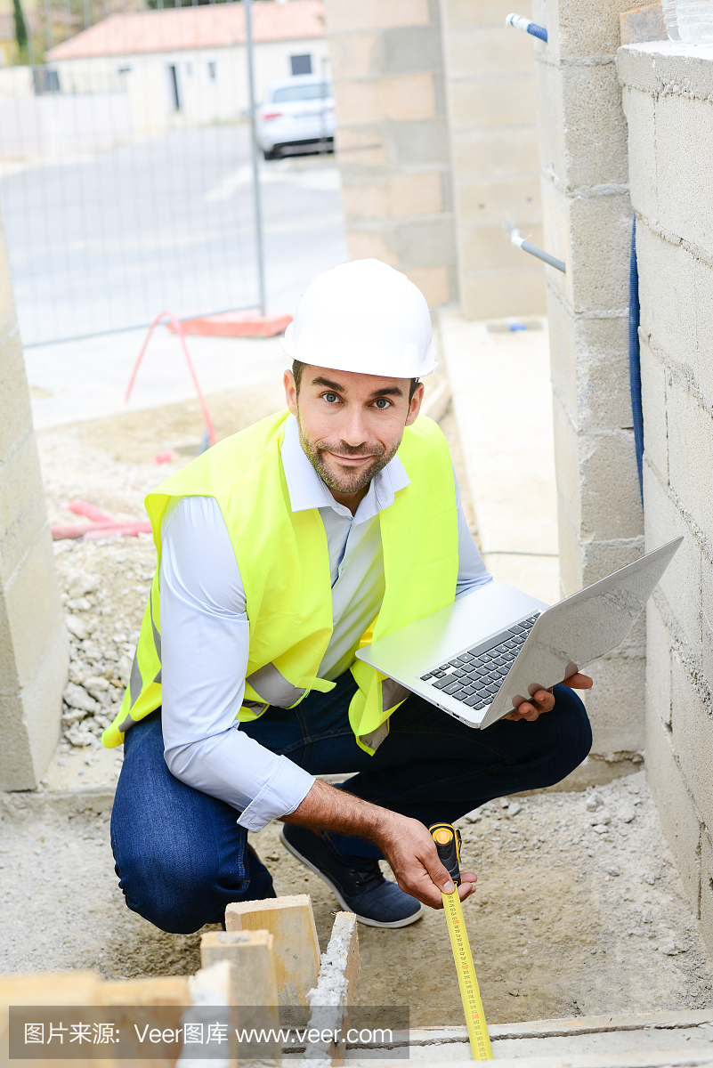 英俊的年轻人工头建筑师监督一个新房子建筑工地